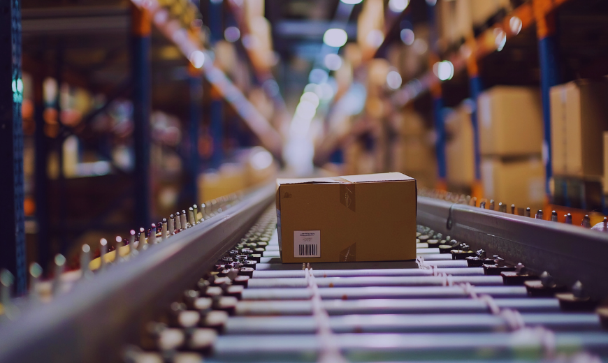 Cardboard box on conveyor belt in warehouse supply chain facility, illustrating global trade logistics and distribution processes.